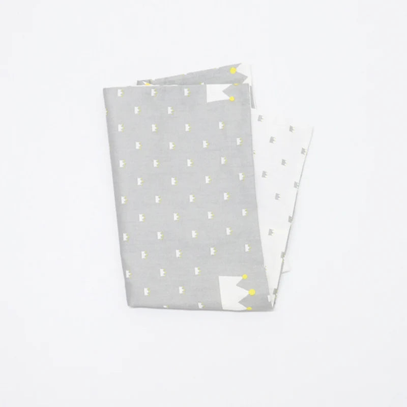 A stack of soft cotton baby pillow covers in light gray with yellow stitching details.