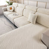 A light cream plush elastic sofa cushion cover with vertical ribbed texture and a white decorative pillow.