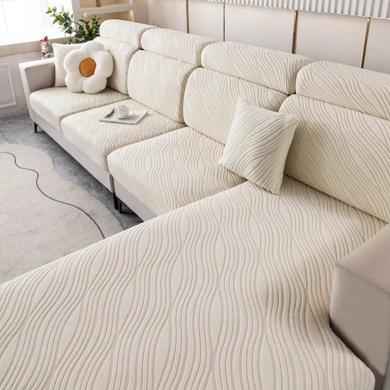 A light cream plush elastic sofa cushion cover with vertical ribbed texture and a white decorative pillow.