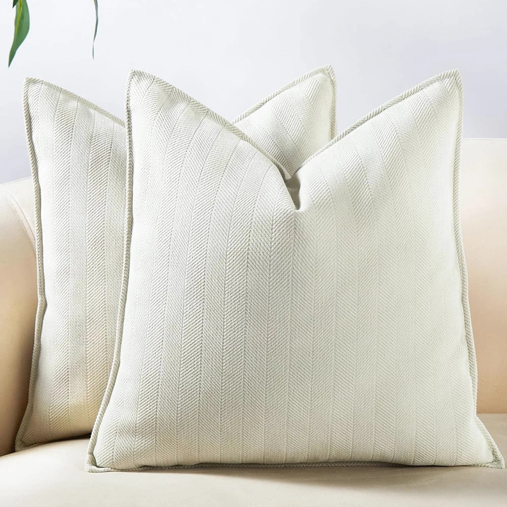 A cream-colored chenille throw pillow cover with vertical ribbing displayed on a light sofa.