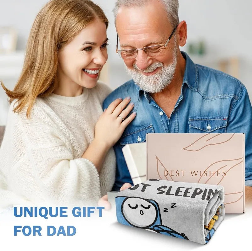 A man and woman smiling while holding a gray knitted blanket for dad