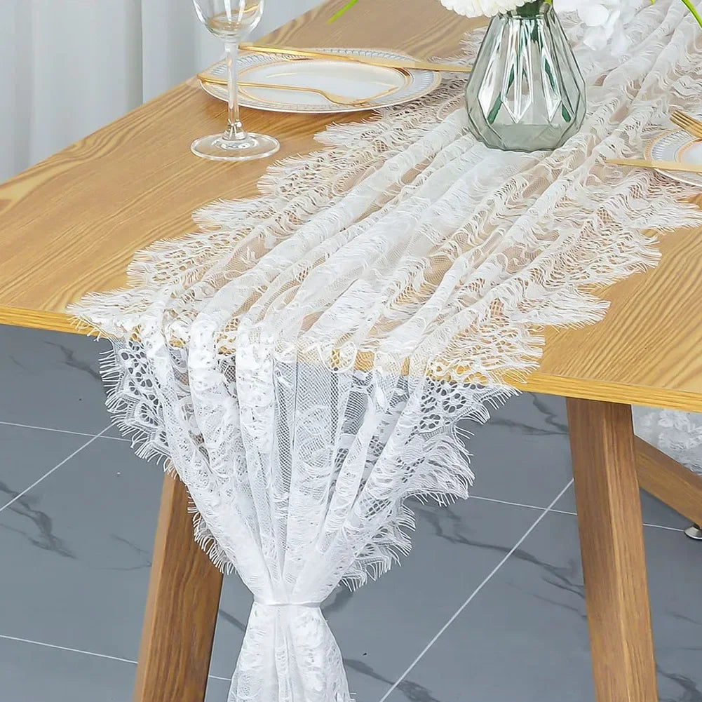 White embroidered floral lace table runner draped on a wooden table.
