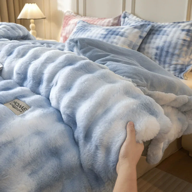 A close-up view of a light blue plush rabbit quilt comforter being touched on a bed.