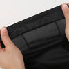 A hand is holding a black paisley print unisex headwrap, showing the fabric texture and adjustable strap.