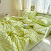 A bright lime green summer seersucker quilt comforter spread out on a bed with white curtains and a lamp.