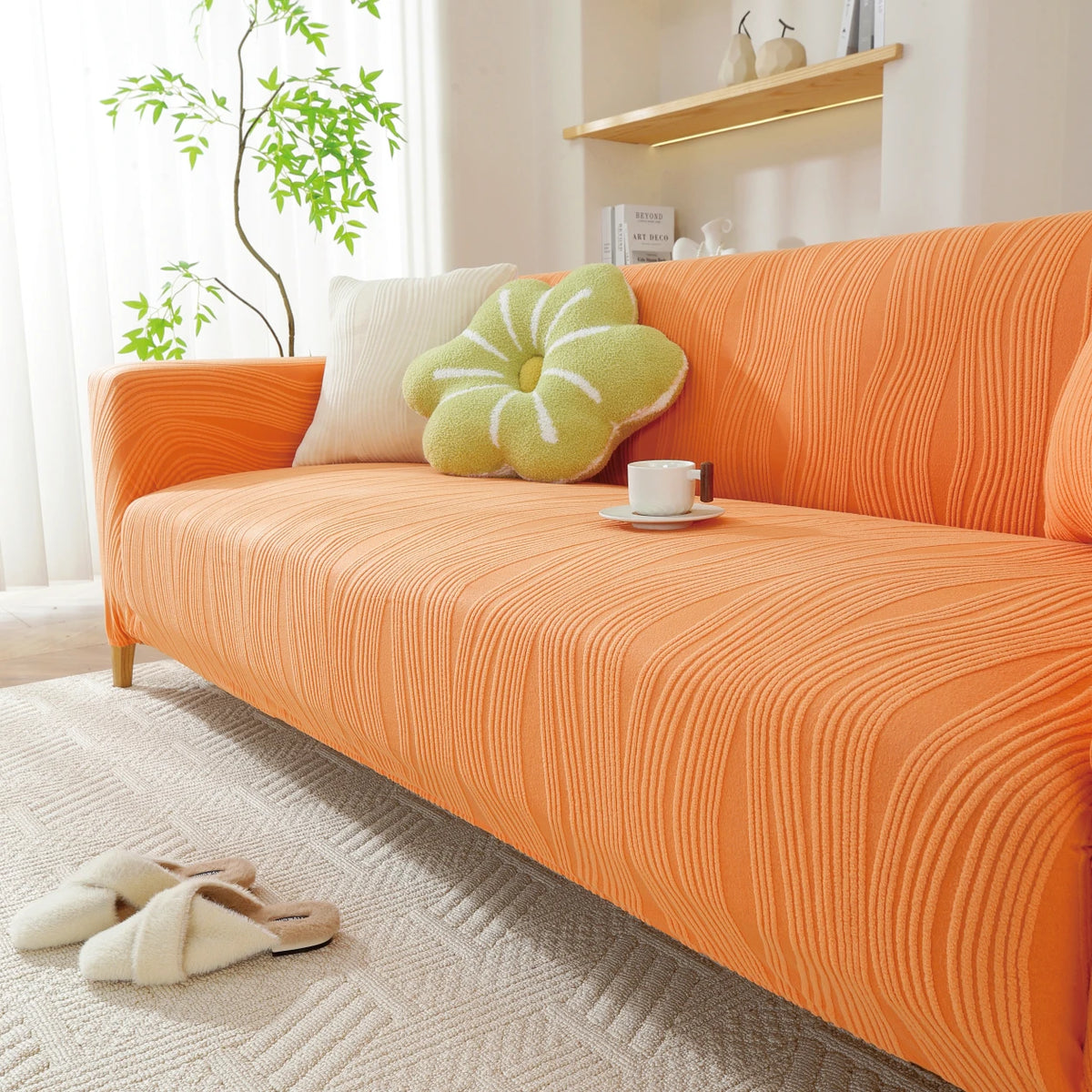An orange stretchable sofa cover with a vertical line pattern is displayed on a light rug.