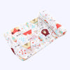 A folded white muslin swaddle blanket featuring colorful geometric patterns and a brown bear design.