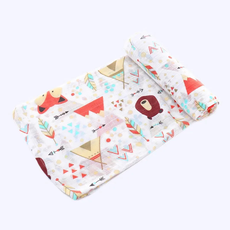 A folded white muslin swaddle blanket featuring colorful geometric patterns and a brown bear design.