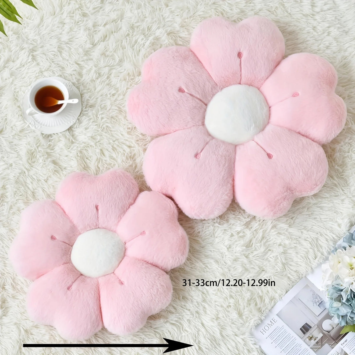 Pink plush daisy flower throw pillow resting on a white fluffy surface.