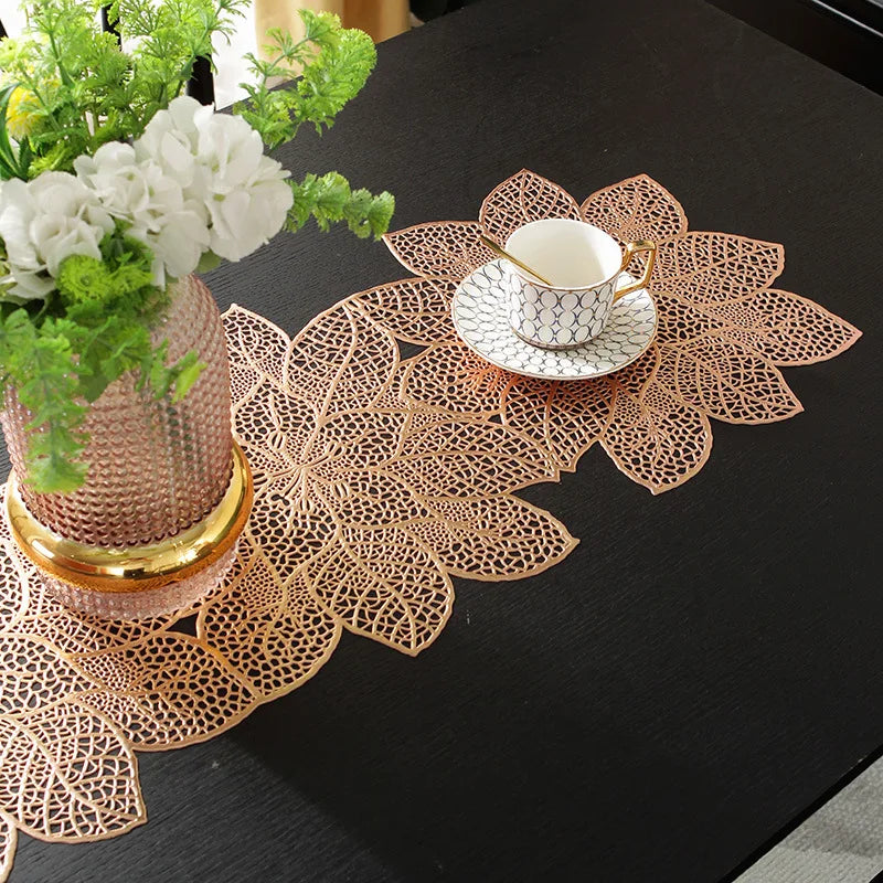 A gold-toned ceramic teacup rests on a decorative, laser-cut wooden placemat set on a dark table.