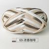 A ball of hand-dyed fabric strip yarn in beige, white, and gray stripes for crochet and knitting.
