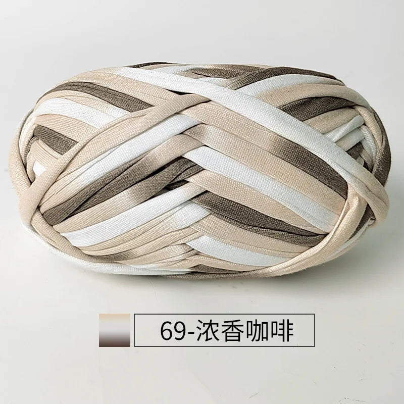 A ball of hand-dyed fabric strip yarn in beige, white, and gray stripes for crochet and knitting.