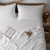 White French stone washed linen bedding set with pillows and a folded book on a bed