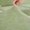 A hand is adjusting the fabric of a sage green stretchable chenille sofa cushion cover.