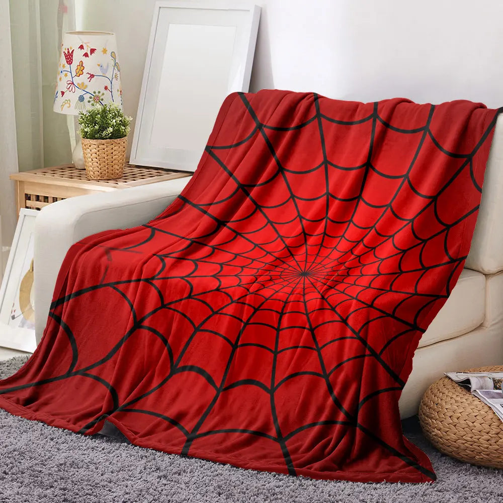 A vibrant red throw blanket featuring a black symmetrical spider web pattern draped over a light-colored sofa.