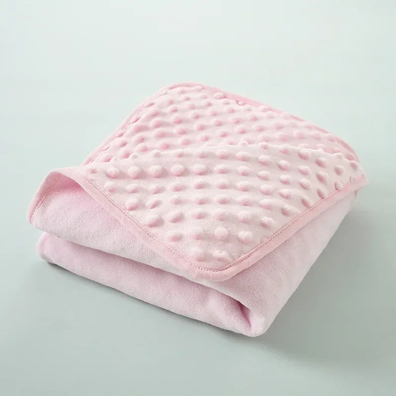 A stack of pink, quilted fleece swaddle blankets for infants and toddlers.