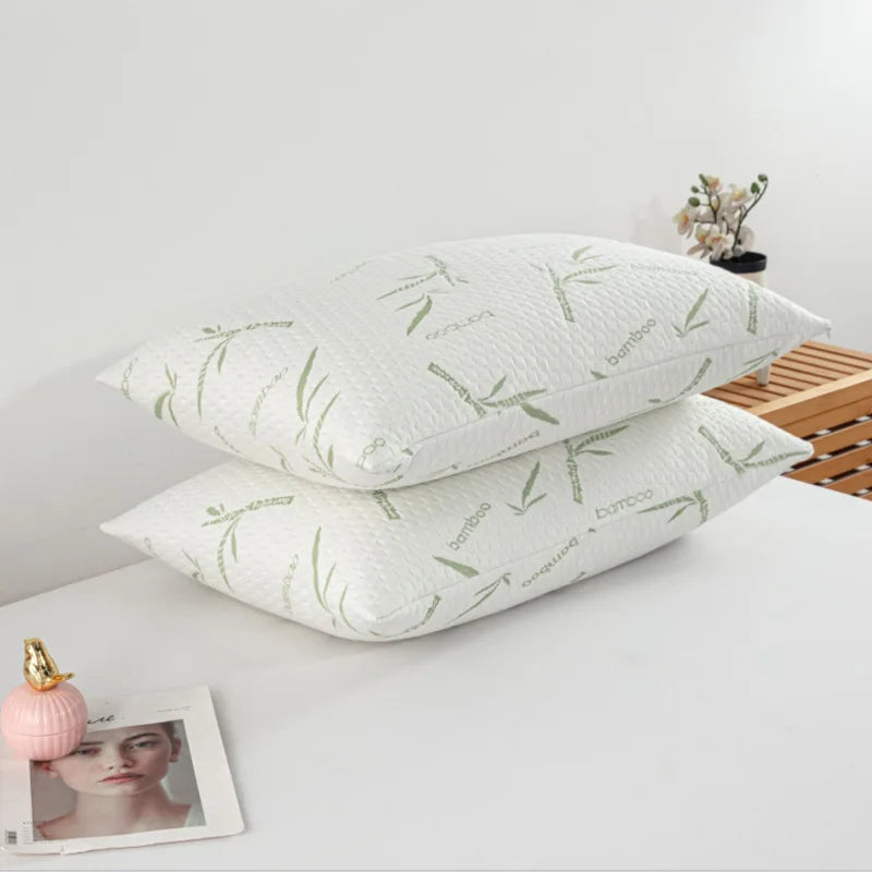 Two white bamboo pillow protectors lying on a white surface next to a framed photo.