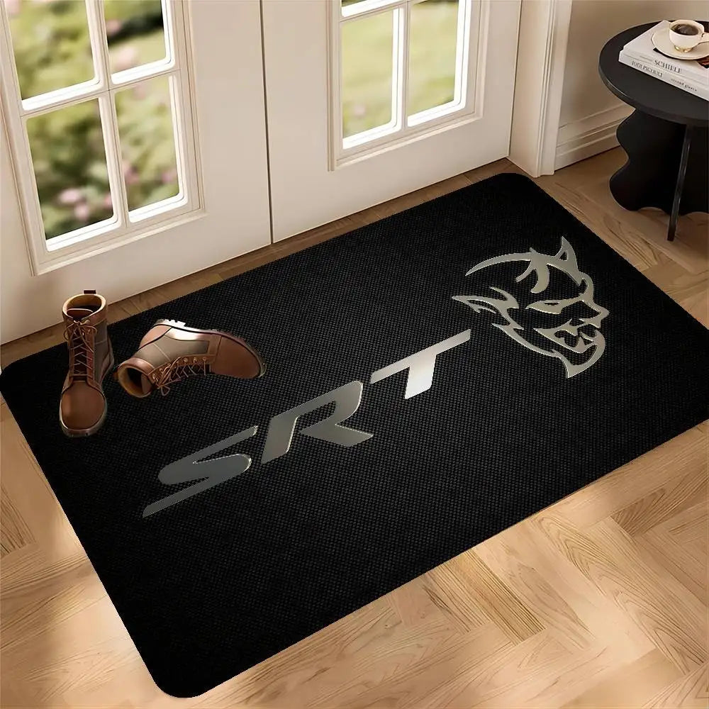 A black anti-slip door mat featuring a silver graphic design of a stylized face and the letters SRT on a light wood floor.