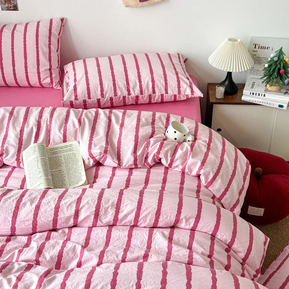 Pink striped duvet cover set and pillows with a book on the bed.