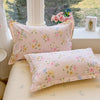 A pink floral duvet cover and pillow set displayed on a light-colored surface near a window.