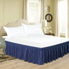 A white bed with a navy blue ruffle skirt and bedding set in a bright, light-colored room.