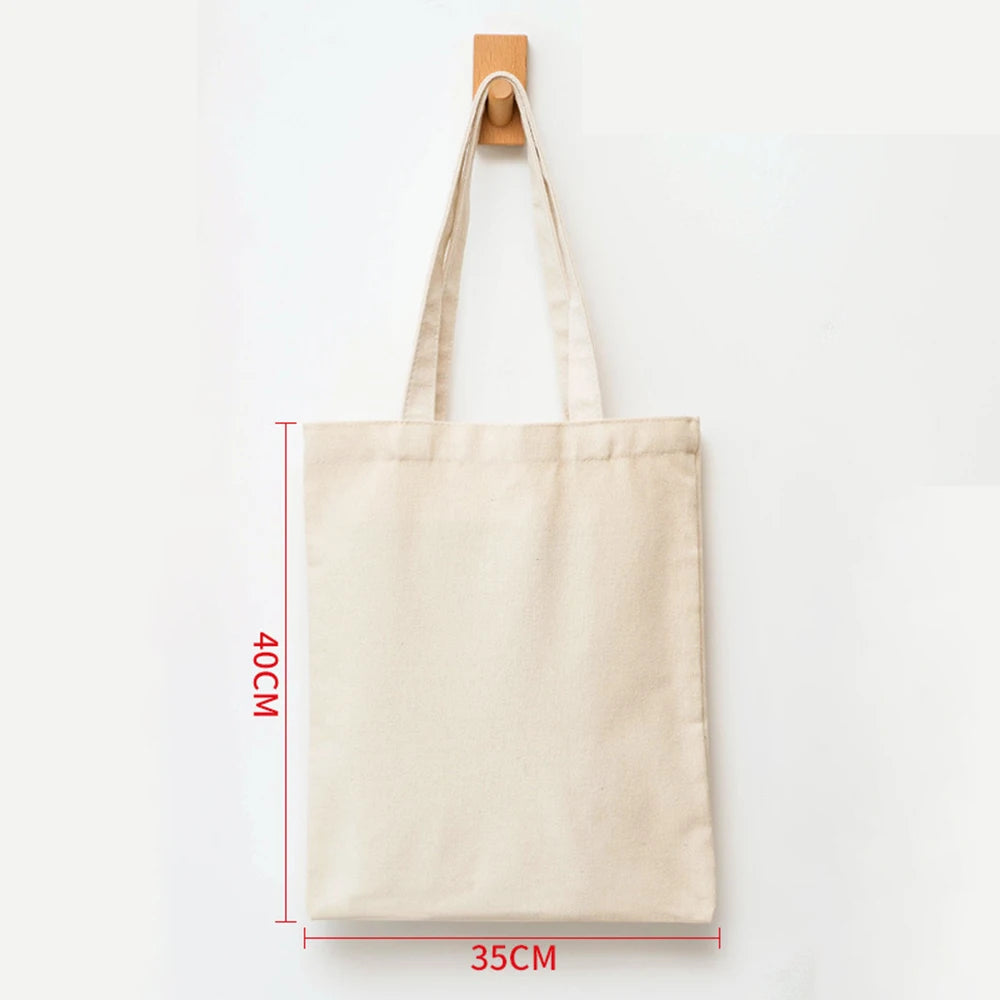 A beige canvas tote bag hanging by its wooden hanger against a white background.