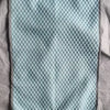 Light blue textured ice silk cooling pillowcase resting on a wrinkled gray fabric.