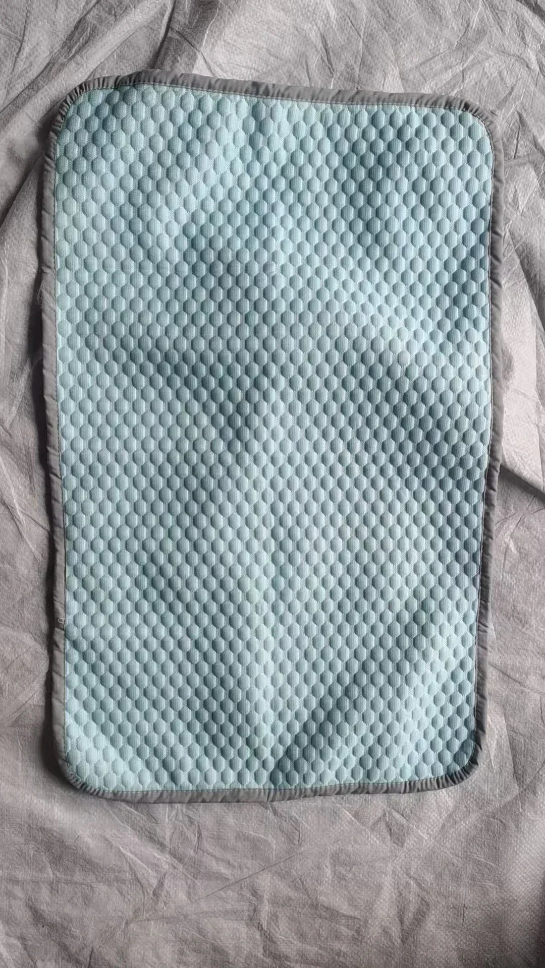 Light blue textured ice silk cooling pillowcase resting on a wrinkled gray fabric.