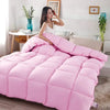 A pink quilted comforter or duvet is displayed on a bed in a bright room.