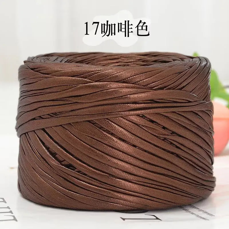 A spool of metallic brown cake yarn tightly wound for crafting.
