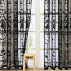 Black sheer curtain featuring intricate pearl and lace embroidery hanging in a window frame.