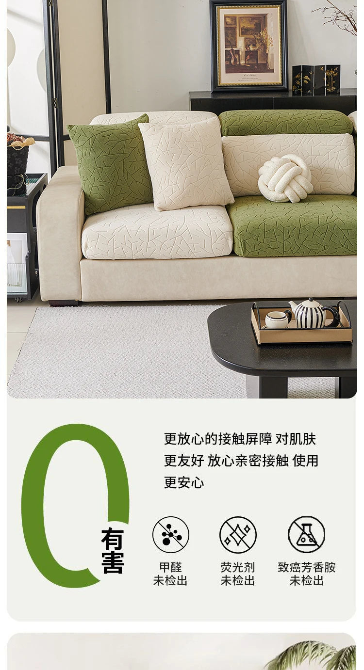 A beige sofa covered with a green patterned jacquard fabric, featuring decorative pillows and a white knitted accent.