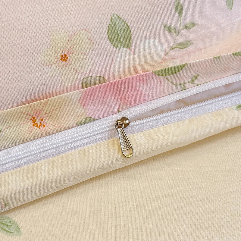 A close-up of a light pink floral patterned cotton duvet cover and pillow set with a zipper closure.