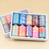 A box filled with various colorful rainbow sewing threads in spools, arranged neatly for sale.