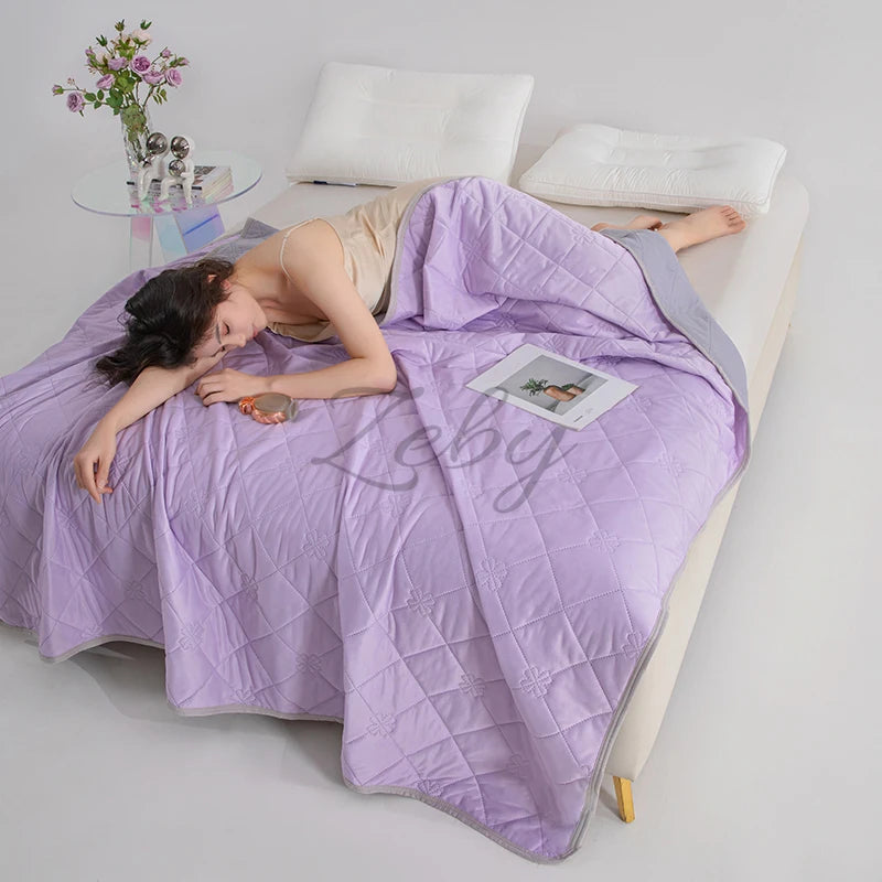 A purple breathable cooling blanket is draped over a person lying down on a white surface.