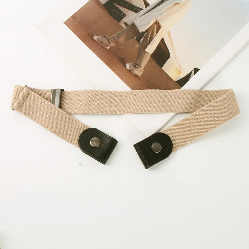 A beige elastic waist belt with black hardware is shown next to a piece of paper and clothing.