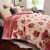 A pink and cream floral weighted blanket draped over a bed in a bright room.