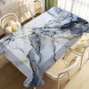 A marble-patterned tablecloth featuring gray and white marble with gold veining on a wooden table.