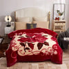 A deep red weighted blanket with a floral pattern is displayed on a bed in a bright room.