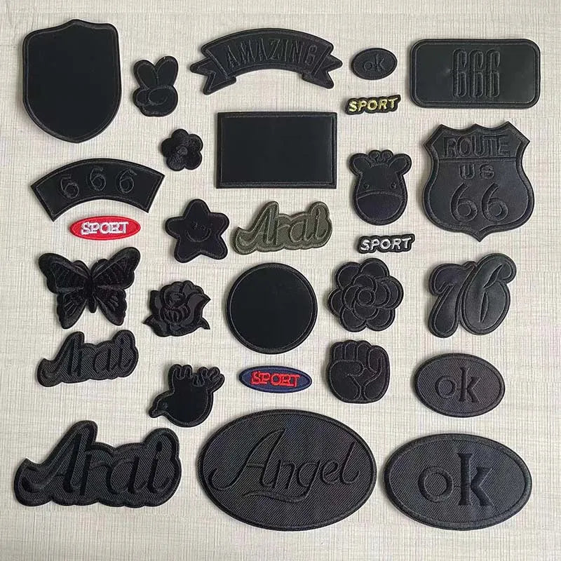 A collection of black embroidered leather patches featuring various designs like a shield, text, and symbols.