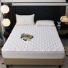 A white quilted mattress protector is displayed on a bed, featuring a diamond pattern and resting on a beige base.