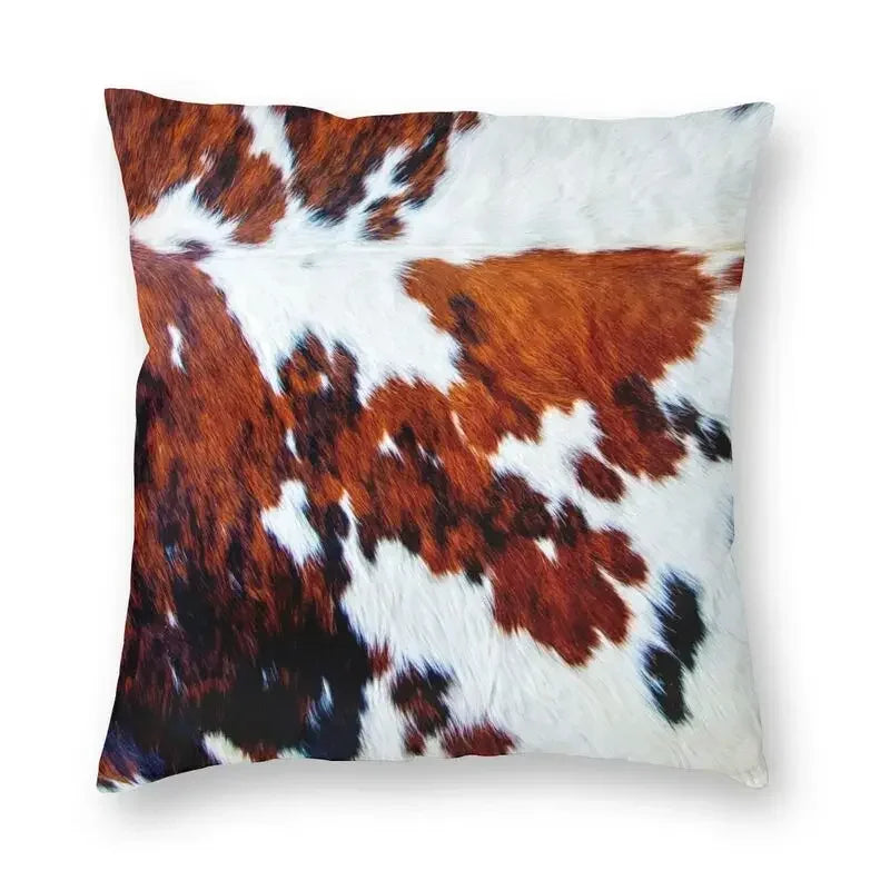 A square cushion cover made of faux fur cowhide print featuring brown and white patches.