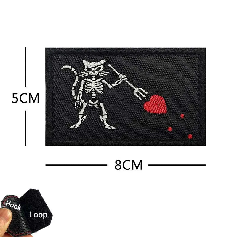 Black embroidered patch featuring a skeleton cat holding a heart and a stick, with dimensions marked.