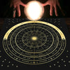 A hand holds a glowing orb above an astrological tarot card tablecloth showing zodiac signs and constellations.