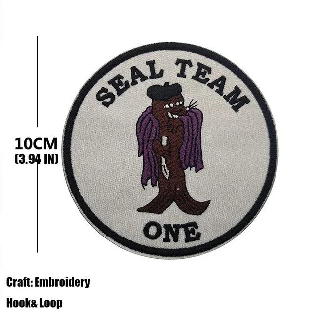 A round gray embroidered patch for a Seal Team member featuring a stylized dark brown figure and the text ONE.