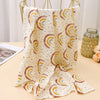 A beige and white printable cotton crib sheet draped on a gold hanger.