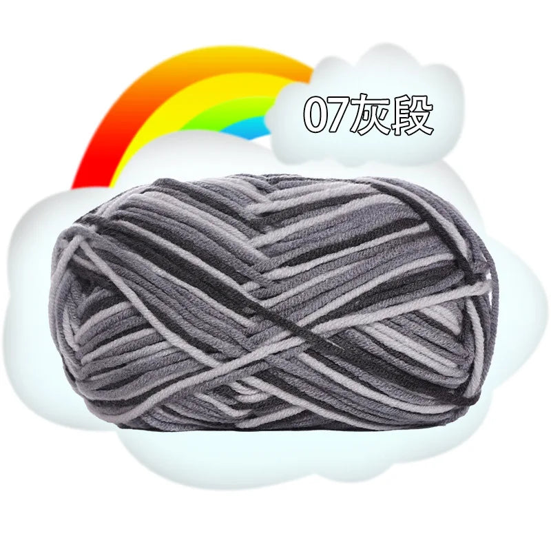A ball of gray and white premium milk cotton yarn with a rainbow in the background.