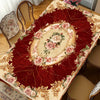A richly colored red tablecloth featuring an elegant floral pattern of pink and green roses on a vintage-style table.