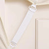 White adjustable bed sheet and quilt holder set hanging on a light-colored wooden surface