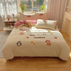 A beige embroidered bedding set featuring cute animal designs like bears and penguins on a bed.